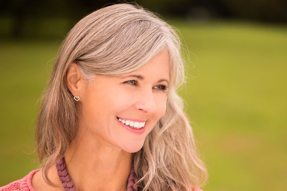 A portrait of an attractive older woman smiling and looking to the side