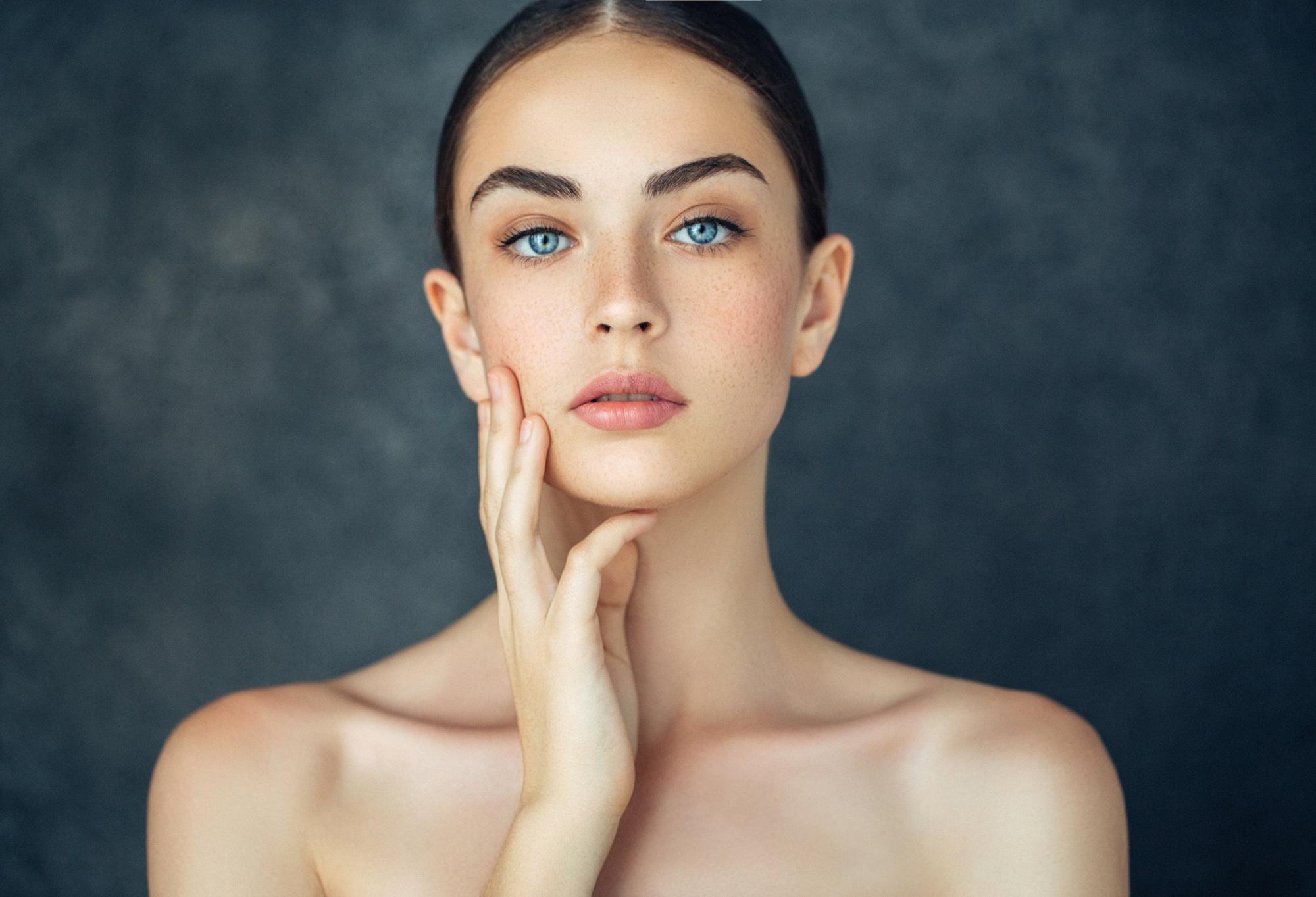 plastic surgery patient model with exposed shoulders holding her fingers up to her cheek