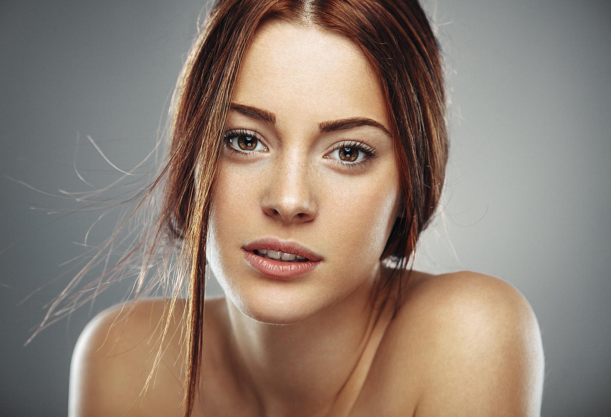 red haired plastic surgery patient model with bare shoulders smiling slightly